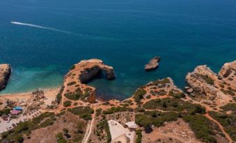 an aerial view of a beach with a small body of water surrounded by rocks and trees at Vila Alba Resort