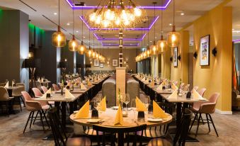 a long dining room with multiple tables set for a formal event , each table having yellow tablecloths and white napkins at Leonardo Offenbach Frankfurt