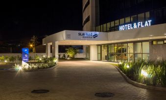 "a hotel entrance at night , with the name "" slavieh "" written on the building and surrounded by trees" at Slaviero Campina Grande