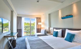 a hotel room with a king - sized bed , a couch , and a balcony overlooking the ocean at Park Plaza Belvedere Medulin