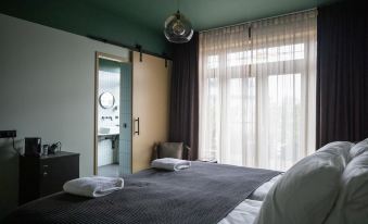 a modern bedroom with a large window , white curtains , and a bed with white towels on it at Mr Lewis Zandvoort