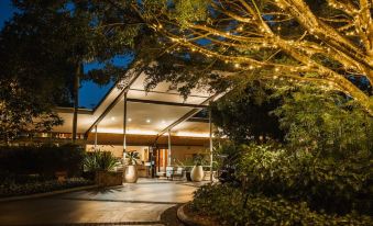 a modern , minimalist house with a large outdoor dining area and trees decorated with lights at night at Crystalbrook Byron