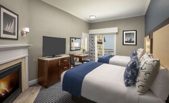 a hotel room with two beds , a tv , and a desk , all decorated in neutral colors at Nantasket Beach Resort