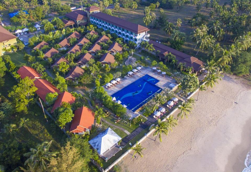 aerial view of a resort on the beach , with multiple buildings and a large pool surrounded by palm trees at Kuiburi Hotel & Resort