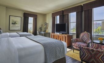 a hotel room with two beds , a tv , and a chair , all situated near large windows at Graduate Berkeley