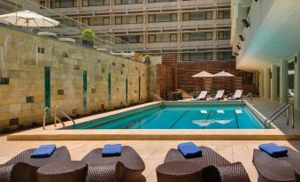 The building has an outdoor lounge area with a swimming pool, chairs, and tables at Marco Polo Hongkong Hotel