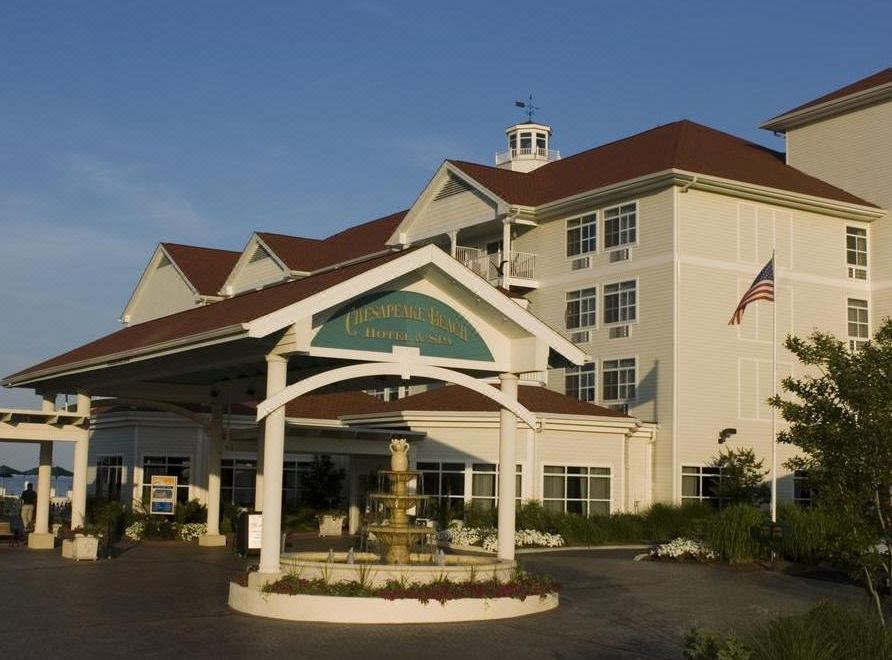 a large hotel with a white exterior and a fountain in front of it , under a clear blue sky at Rod 'N' Reel Resort