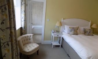 a bedroom with a bed , nightstand , and chair is shown next to a door at Flynns of Termonfeckin Boutique Hotel