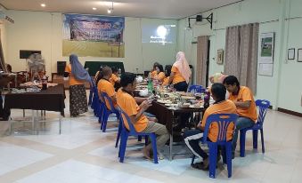 a group of people wearing orange shirts are sitting at a table in a room at Payabangsa Resort