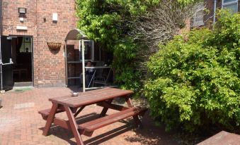 a brick courtyard with two picnic tables and a tree , providing a pleasant outdoor seating area at The Shoes