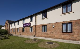 "a modern building with multiple floors , a sign that reads "" premier inn ,"" and two flower pots in the courtyard" at Silverstone