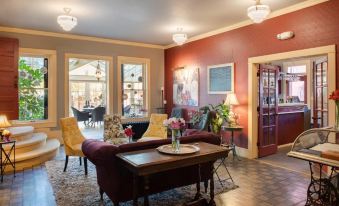 a cozy living room with red walls , a wooden coffee table , and several chairs arranged around it at Chamberlin Inn