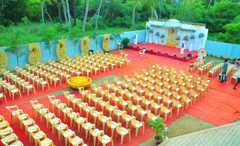 a large outdoor event with rows of chairs arranged in a symmetrical fashion , surrounded by lush greenery and a white building at OYO Flagship Hotel Priso