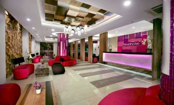 a modern hotel lobby with red and black furniture , a check - in desk , and multiple chairs at favehotel Langko Mataram - Lombok