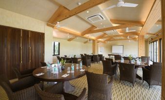 a large conference room with multiple round tables , chairs , and a projector screen , all set up for an event at Beleza by the Beach