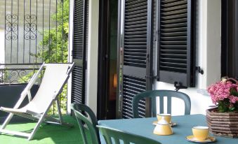 a green terrace with two chairs and a table set for tea , surrounded by flowers and plants at Bellavista