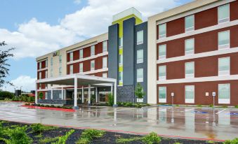 a large building with a yellow stripe on the side and a covered walkway in front at Home2 Suites by Hilton la Porte