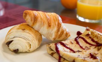 a breakfast plate with a croissant , jam , and a slice of cheese , accompanied by a cup of coffee and orange juice at Auberge la Tomette, the Originals Relais