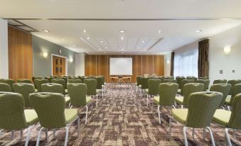 a large conference room with rows of chairs arranged in front of a projector screen at Ramada Plaza by Wyndham Wrexham