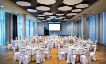 a large banquet hall with multiple round tables and chairs set up for a formal event at Park Inn by Radisson Katowice