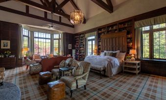 a spacious bedroom with a large bed , multiple chairs , and a bookcase filled with books at The Greystone Inn