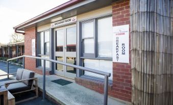 "a brick building with a sign above the entrance that reads "" rest room "" and a window" at Cherry Blossom Motor Inn