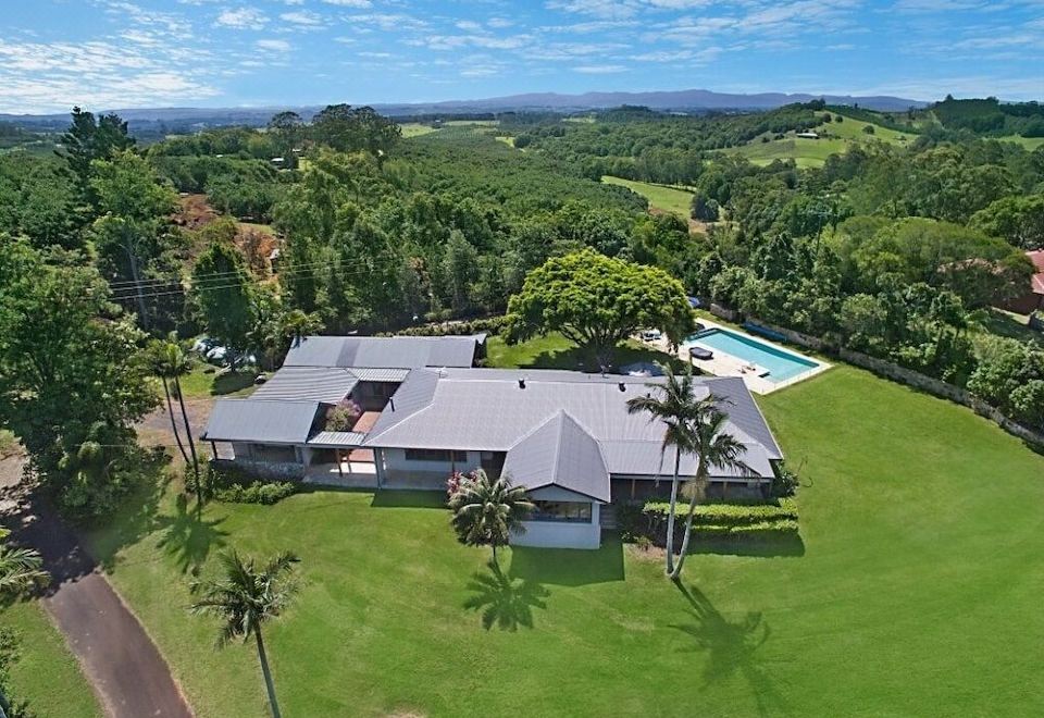 aerial view of a large house surrounded by green grass and trees , with a swimming pool visible in the background at Ferncrest