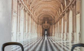 a long , narrow hallway with white marble walls and columns , leading to a room with a statue on the left side at Ibis Styles Paris Mairie de Montreuil