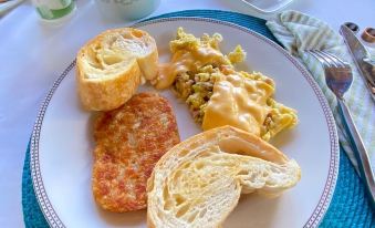 a plate of food on a dining table , including a variety of dishes such as bread , eggs , and meat at Hacienda Tres Casitas