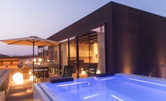 a modern building with a hot tub on its rooftop , surrounded by glass windows and a wooden deck at Alba Palace Hotel