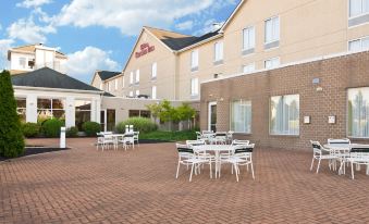 a courtyard with several tables and chairs set up for outdoor dining , surrounded by a large building at Hilton Garden Inn Wooster