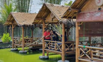 a group of people standing on a wooden platform , surrounded by bamboo and water , with bamboo poles extending into the water below at Borobudur Bed & Breakfast