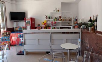 a room with a white counter and chairs , shelves filled with various items , and a television mounted on the wall at Hotel Vent de Mar