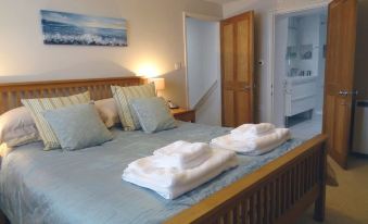 a large bed with a wooden headboard and white towels on it , creating a cozy atmosphere at Lakeside