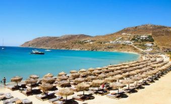 a beach scene with rows of umbrellas and chairs set up on the sand , overlooking a body of water at The Summit of Mykonos