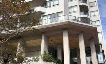 a tall , white apartment building with many balconies and trees in front of it , under a clear blue sky at Milson Serviced Apartments