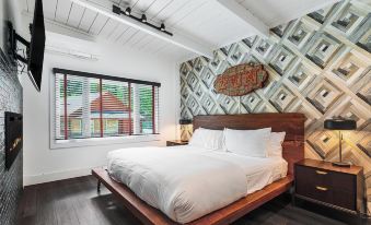 a large bed with white linens is situated in a room with wooden floors and walls , under a hanging light at The Creekstone