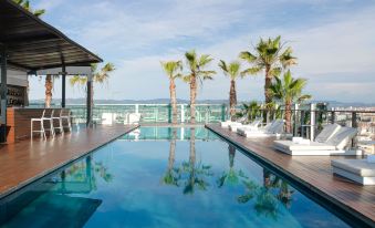 a large swimming pool with a few lounge chairs and palm trees in the background at Renaissance Barcelona Fira Hotel