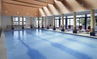 a large indoor swimming pool with a row of lounge chairs and a long table in the middle at Grand Mercure Petra