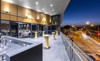 a large , modern building with a balcony and outdoor dining area , illuminated by lights at night at Hotel Grand Chancellor Brisbane
