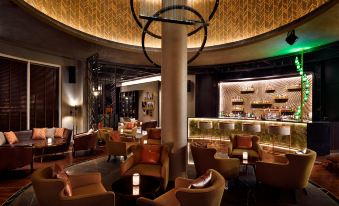 a luxurious bar with leather chairs , a large bar area , and a chandelier , creating an inviting atmosphere at Movenpick Hotel Bahrain