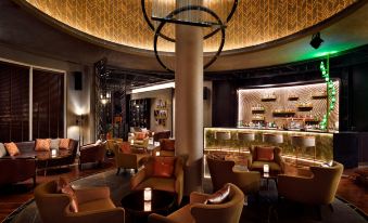 a luxurious bar with leather chairs , a large bar area , and a chandelier , creating an inviting atmosphere at Mövenpick Bahrain