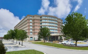 a large building with many windows is surrounded by trees and cars in the lot at Renaissance Chicago Glenview Suites Hotel