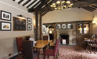 a dining room with a wooden table and chairs , a chandelier hanging from the ceiling , and framed pictures on the wall at Silverstone