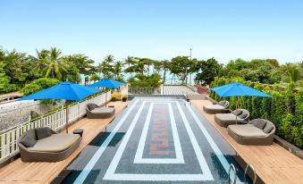 The rooftop of the hotel features a swimming pool with chairs and umbrellas, providing a picturesque view of the outdoor seating area at Mera Mare Pattaya