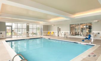 an indoor swimming pool with a white ceiling and walls , surrounded by chairs and tables at Homewood Suites by Hilton Frederick