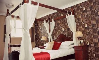 a bedroom with a four - poster bed covered in white sheets and red blankets , creating a cozy atmosphere at Dartmoor Lodge Hotel