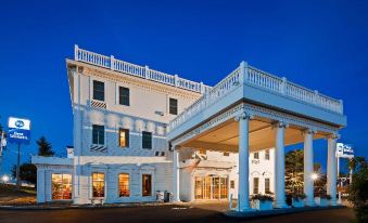 a large white hotel building with a covered porch and blue skies in the background at Best Western White House Inn