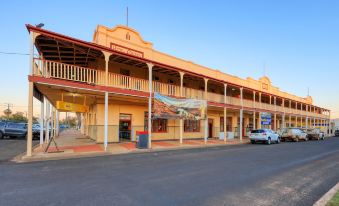 a large yellow building with a carpark and advertisements on the side , set against a clear blue sky at Hotel Corones