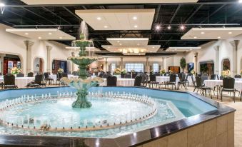 a large dining room with a fountain in the center , surrounded by tables and chairs at Quality Inn Festus